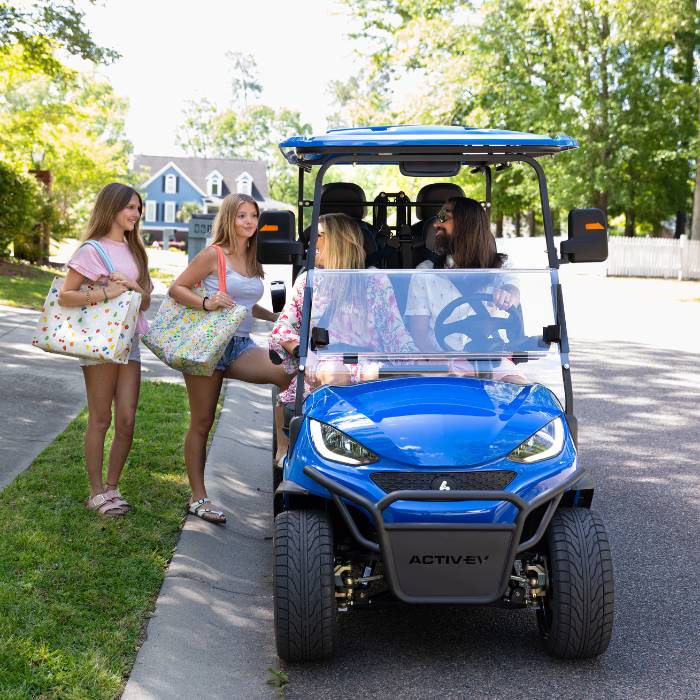 Family loading into a blue Back Bay Rentals six-seater golf cart for a day out.